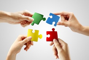 Hands and puzzle on gray background. Teamwork solving a puzzle