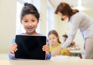 little school girl with tablet pc over classroom